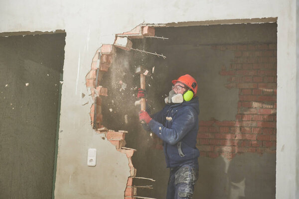 demolition work and rearrangement. worker with sledgehammer destroying wall