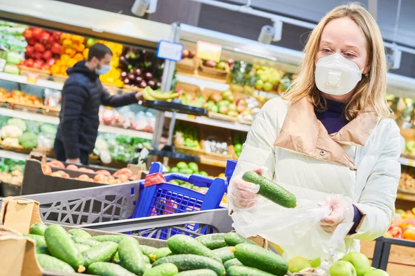 Mujer con máscara y guantes protectores comprando comida en tienda en coronavirus epidemia —  Fotos de Stock