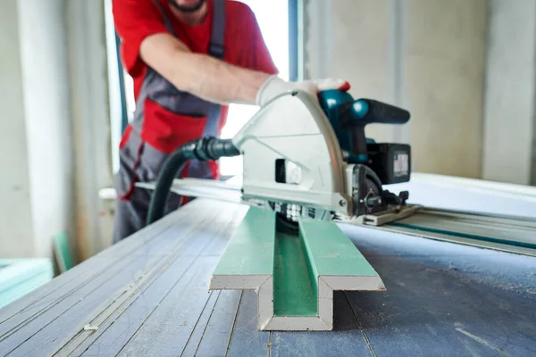 Drywall construction. worker sawing gypsum plasterboard by hand-held machine. Focus on gypsum — Stock Photo, Image