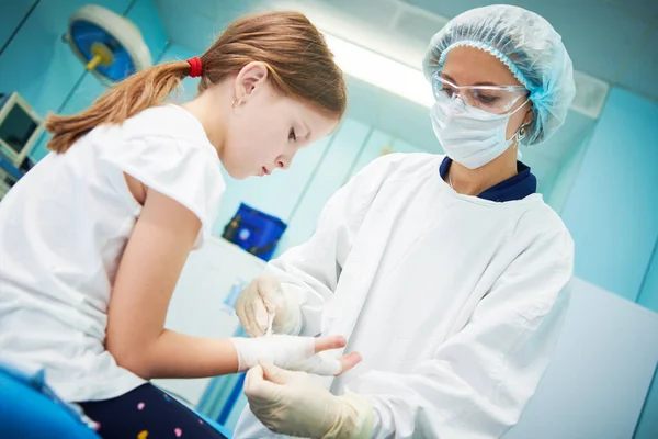 Mujer cirujano médico vendaje niños mano en la clínica —  Fotos de Stock