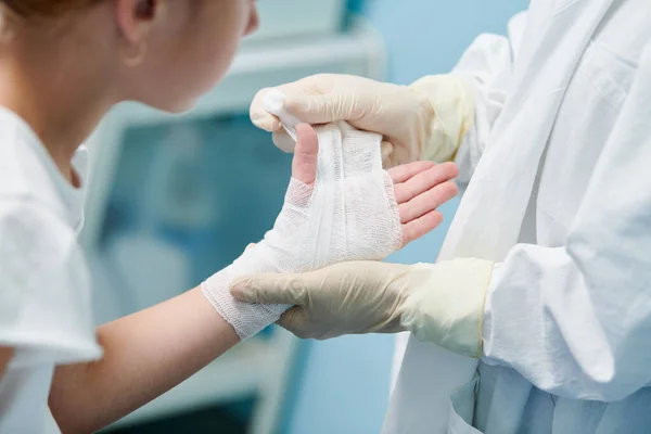 Klinikte çocukları el ele bandajlayan cerrah doktor. — Stok fotoğraf