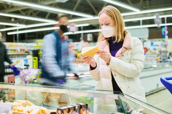 Mujer en máscara comprar comida en tienda en la epidemia de coronavirus — Foto de Stock