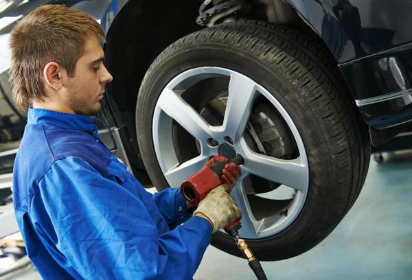 Auto mechanic screwing car wheel by wrench Stock Photo