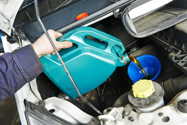 Car mechanic pouring oil into motor engine — Stock Photo, Image