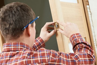 Male carpenter at lock installation clipart