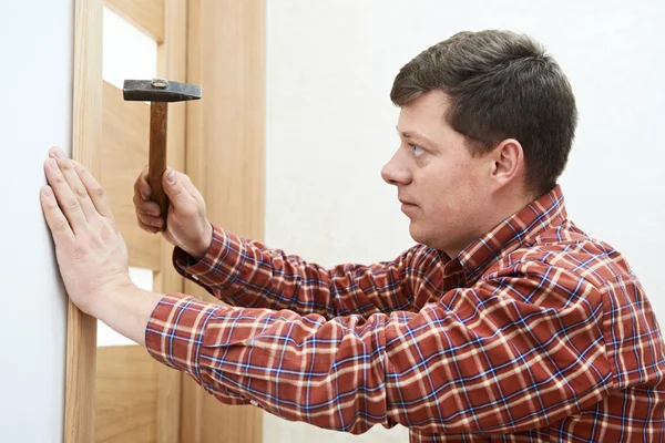 Timmerman tijdens de installatie van de deur — Stockfoto