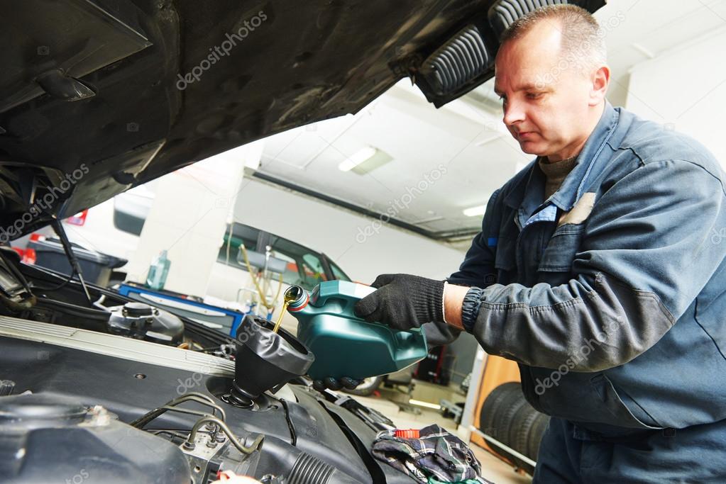 car mechanic pouring oil into motor engine