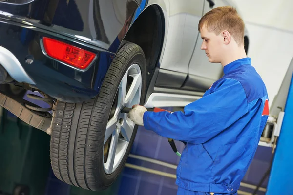 Auto mechanic screwing car wheel by wrench — Stock Photo, Image