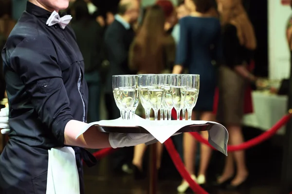 Servitören med fack och vin glasögon på fest — Stockfoto