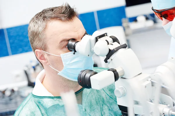 Dentista trabalha com microscópio — Fotografia de Stock