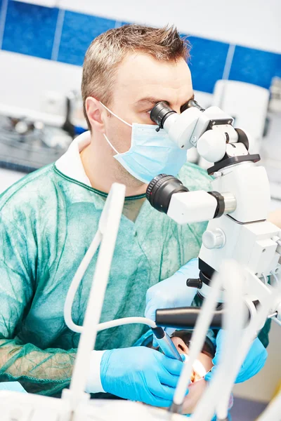 Dentista trabalha com microscópio — Fotografia de Stock