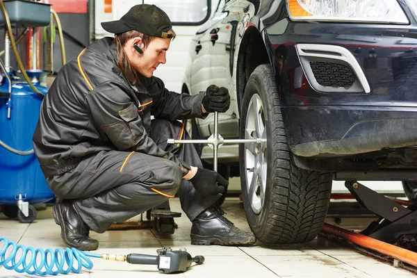 Auto mechanic screwing car wheel by wrench — Stock Photo, Image