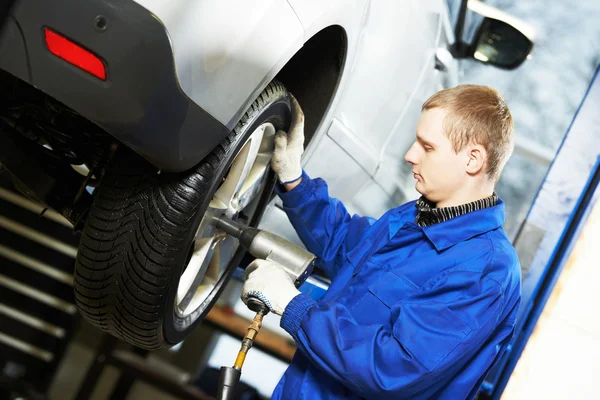 Auto mechanic screwing car wheel by wrench Stock Photo