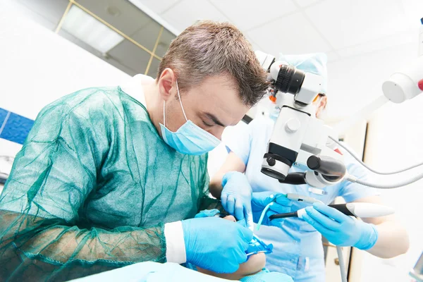 Dentista que trabalha com microscópio no consultório odontológico — Fotografia de Stock