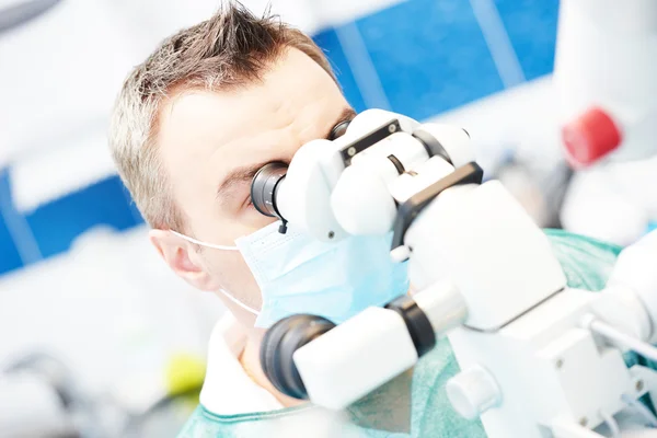Dentista trabajando con microscopio en consultorio de odontología —  Fotos de Stock