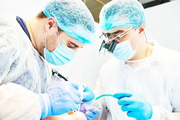 Dentista em uniforme executar operação no escritório de odontologia — Fotografia de Stock