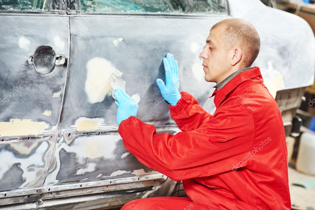 worker applying car body repair putty