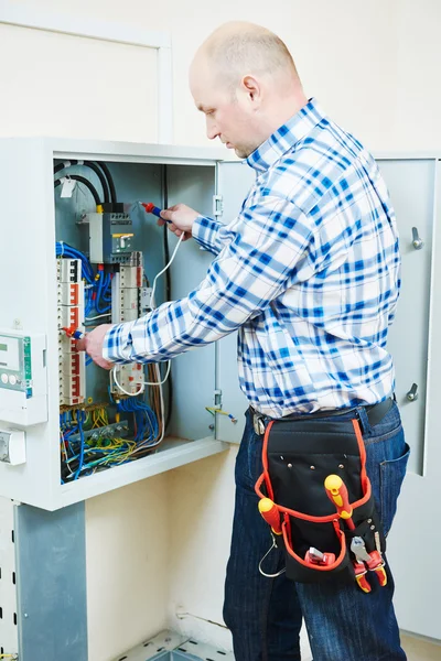 Eletricista trabalha com medidor elétrico testador na caixa de fusíveis — Fotografia de Stock