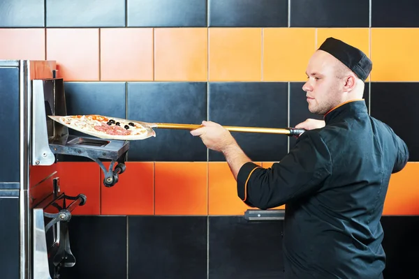 Kocken baker cook att sätta pizza i ugnen — Stockfoto