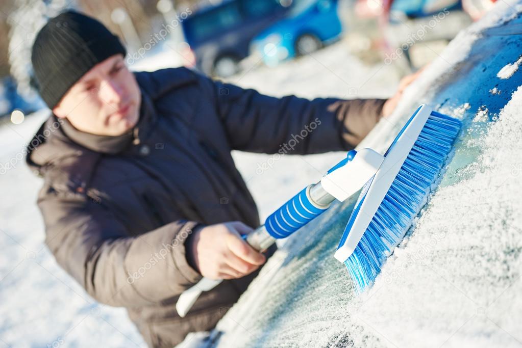man cleaning car from snow