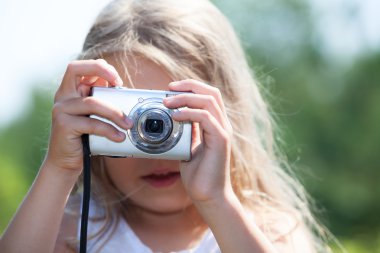 Dijital kamera tutan ve fotoğraf çeken genç sarışın kız.