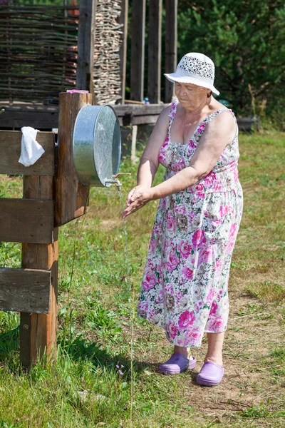 身穿防晒衣的白人老年妇女在洗衣店洗手 — 图库照片
