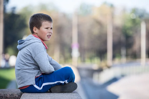 花崗岩のプレートの端に座っている思慮深い少年は 距離を見て — ストック写真