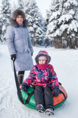 Yaşlı anne ve küçük çocuk portresi. Ormanda kar boruları var.