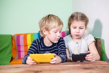 Küçük çocuklar akıllı telefon kullanıyor ve birlikte konuşuyorlar.