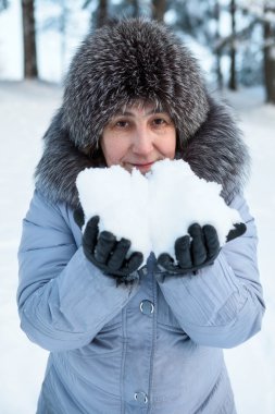 Ellerinde karla gülümseyen olgun beyaz kadın portresi.