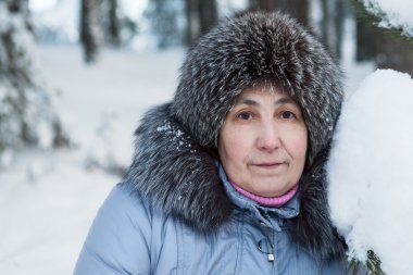 Kışın kürk manto ve şapka giyen güzel olgun bir kadın.