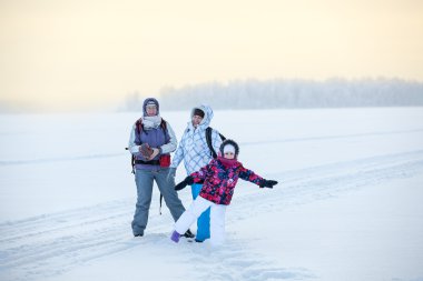 Soğuk havada donmuş gölün buzunda duran üç farklı yaşta kadın.