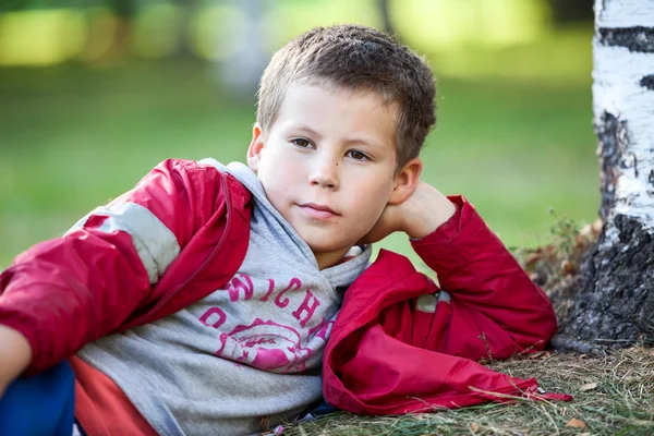 Красивый Кавказский Мальчик Красной Куртке Лежит Рядом Деревом Осеннем Парке — стоковое фото