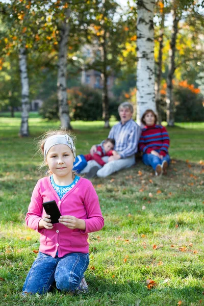 Junges Mädchen Blickt Die Kamera Wenn Mit Handy Gras Sitzt — Stockfoto