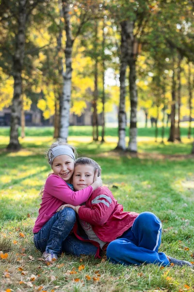 Lachende Kinderen Omhelzend Het Gras Het Herfstpark — Stockfoto