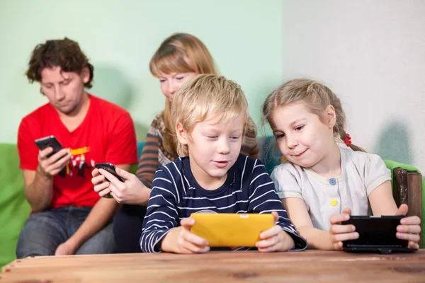 所有的家庭 孩子和家长都坐在一起玩小玩意 用智能手机玩游戏 — 图库照片