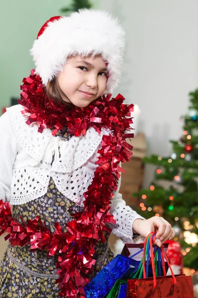 小さな女の子でA赤クリスマスティンセルとともにギフトで彼らの手 — ストック写真