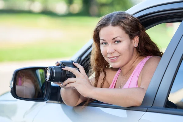 Piękna Kobieta Fotograf Patrząc Aparat Podczas Siedzenia Samochodzie Pochylając Się — Zdjęcie stockowe