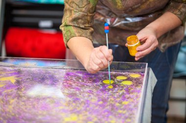 Su yüzeyinde misket mürekkebi olan kadın eller.