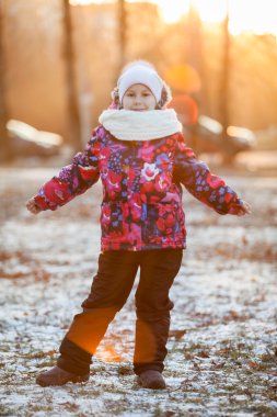 Altı yaşında, sıcacık elbiseli bir kız parkta yürüyüş için, batan güneşin ışınları...