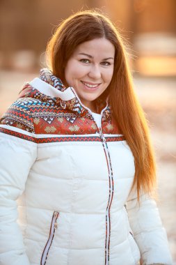 Beyaz ceketli, güneş ışığında gülümseyen güzel bir kadının portresi.