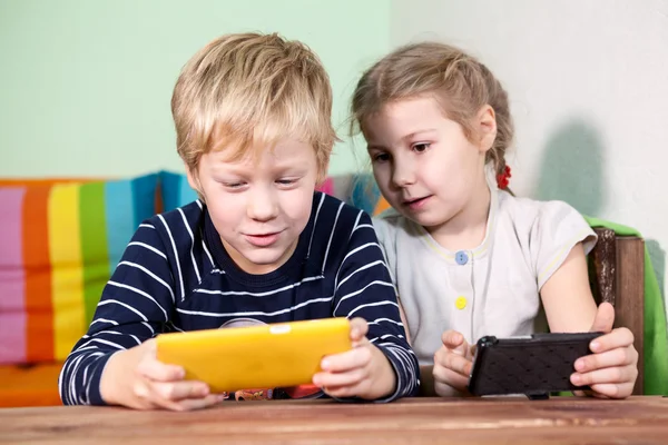 2人の若い白人の子供が携帯電話で遊んでいる — ストック写真