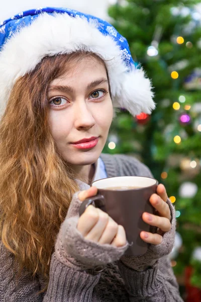 Pretty woman portrait, holding tea mug in hands and looking at camera