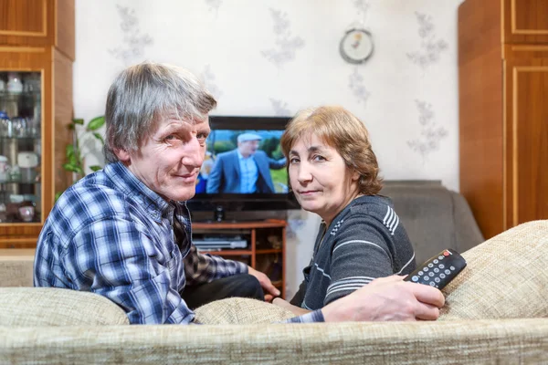 上了年纪的白种人夫妻坐在电视机前 转身坐在沙发上 — 图库照片