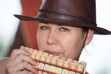 Young country woman in cowboy hat playing the panpipe clipart