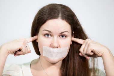 Ağzı mühürlü ve kulakları tıkalı beyaz bir kadın, yakın plan, gri arka plan