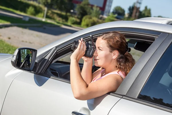 車の窓の外にもたれながらスラーカメラで写真を撮る女 — ストック写真