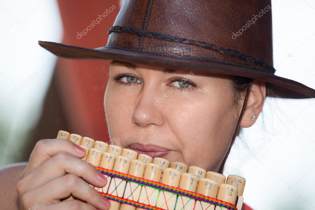 Young country woman in cowboy hat playing the panpipe