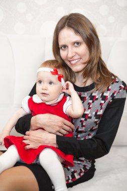 Küçük kızı dizlerinin üstünde neşeli bir anne.