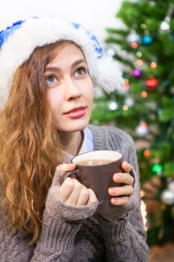Çekici sakin kadın Noel 'de fincandan sıcak çay içiyor.